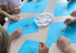 dzieci wykonują prace plastyczne przy stoliku