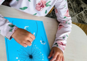 dziecko wykonuje prace plastyczne przy stoliku