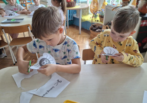 Chłopcy przy stoliku wycinają nożyczkami