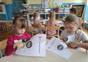 Dziewczynki przy stoliku wycinają nożyczkami