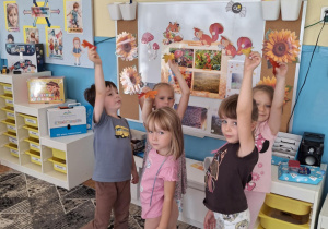 Dzieci w grupie podnoszą liście