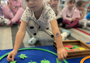 Dziewczynka dokłada do zbioru zielone liście