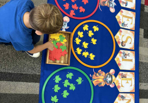 Chłopiec siedzi przed kolorowymi liśćmi