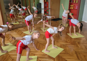 dzieci na sali gimnastycznej ćwiczą pozycję jogi