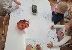 Dzieci przy stoliku odkodowują kartę pracy z jeżem