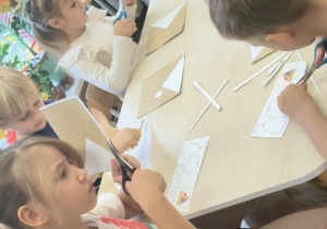 Dzieci wycinają nożyczkami przy stoliku