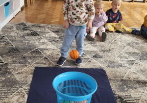 dziecko rzuca piłkę do kosza