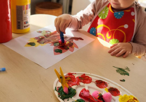 dzieci wykonują pracę plastyczną przy stoliku