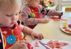 dzieci wykonują pracę plastyczną przy stoliku