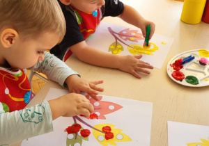 dzieci wykonują pracę plastyczną przy stoliku