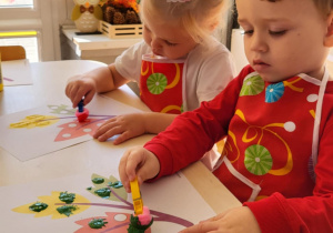 dzieci wykonują pracę plastyczną przy stoliku