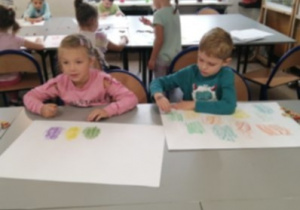 dzieci wykonują prace plastyczne na dużych formatach