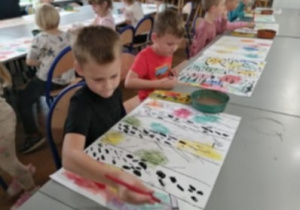 dzieci wykonują prace plastyczne na dużych formatach