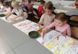 dzieci wykonują prace plastyczne na dużych formatach
