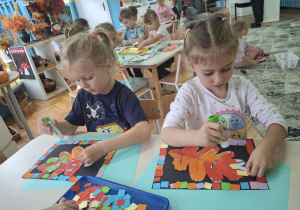 Dzieci przykelajaja kolorowe kartoniki na szablon liścia
