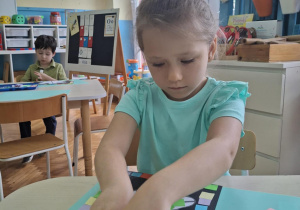Dziewczynka przykleja kolorowe kartoniki na liść dębu