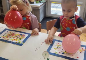 dzieci wykonują pracę plastyczną przy użyciu balonów i farb stemplując