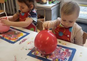 dzieci wykonują pracę plastyczną przy użyciu balonów i farb stemplując