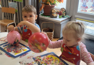 dzieci wykonują pracę plastyczną przy użyciu balonów i farb stemplując