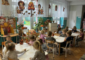 Dzieci pracują przy stolikach wykonując prace plastyczną