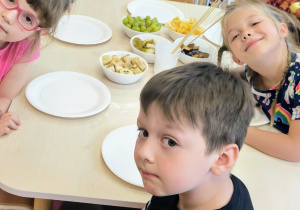 Dzieci siedzą przy stole z owocami