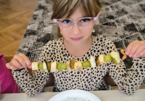 Dziewczynka pokazuje owocowego szaszłyka