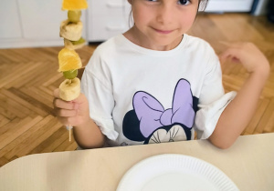 Dziewczynka pokazuje szaszłyka z owoców