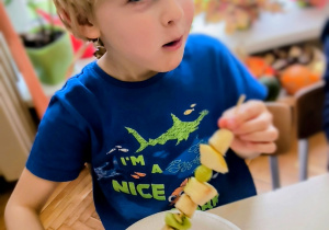 Chłopiec je owoce z szaszłyka