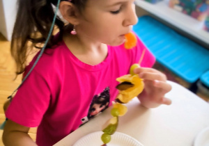 Dziewczynka je owocowego szaszłyka