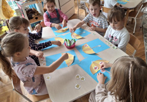 Dzieci przyklejają liście na parasolu
