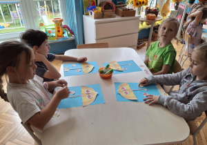 Dzieci układają czerwone liście na parasolu