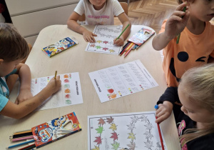 Dzieci przy stole kolorują liście