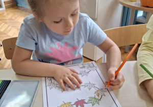 Dziewczynka koloruje liść na pomarańczowo
