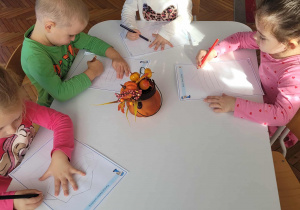 Dzieci przy stoliku rozszyfrowują rysunek łącząc ze soba kropki