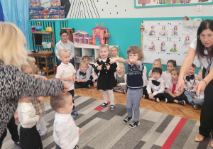 Dzieci pokazują stojąc w kole na swojego kolegę