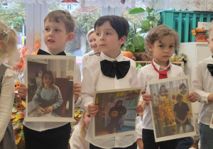 Chłopcy trzymają zdjęcia pani specjalisty, pani nauczycielki i pomocy nauczyciela z grupy pierwszej