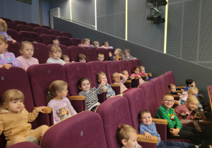 Dzieci siedza na krzesłach w sali kinowej