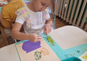 Dziewczynka maluje liść na zielono