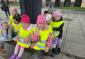 dzieci w kamizelkach siedzą na ławce na Starym Rynku