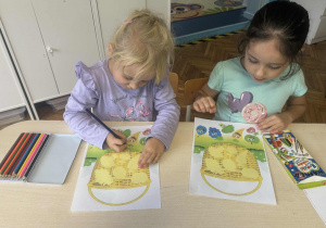 Dzieci siedza przy stole z kartą pracy