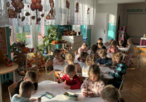Dzieci siedza przy stoliku z nożyczkami