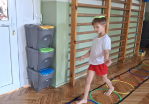 Chłopiec przechodzi z woreczkiem po drabince gimnastycznej