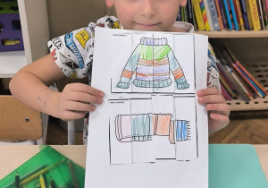 Chłopiec pokazuje ilustrację swetra i szalika