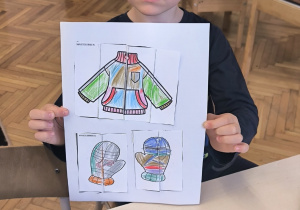 Chłopiec poakzuje puzzle z rękawiczkami i kurtką