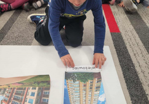 Chłopiec przyklada napis wieżowiec