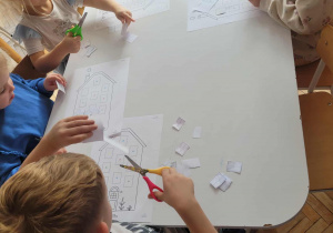 Dzieci przy stoliku wycinaja nożyczkami