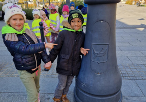 Dziewczynka z chłopcem pokazują herb Łodzi - łódkę