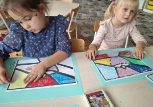 Dziewczynka koloruje na zółto kawałek witrażu