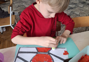 Chłopiec wykleja znicz na kolor czerwony