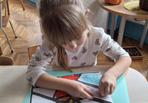Dziewczynka koloruje witraż na filoetowo